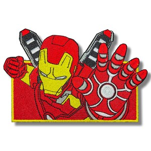 Puede incluir: Parche bordado con Iron Man en una pose dinámica. El parche muestra la armadura roja y dorada de Iron Man, con la mano extendida. El diseño incluye detalles como el casco y los rayos repulsores, sobre un borde amarillo.
