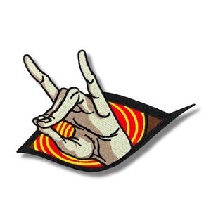 May include: Embroidered patch featuring a hand gesture with the index and pinky fingers extended, forming a rock and roll symbol. The hand is beige, emerging from a stylized eye with red and yellow concentric circles on a black background.