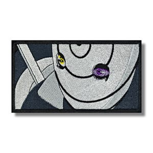 May include: Embroidered patch featuring a stylized character face with a white mask, black outlines, and two visible eyes. One eye is yellow, and the other is purple. The patch has a black border and is set against a white background.