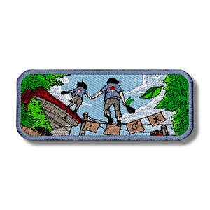 May include: Embroidered patch featuring two figures in blue and grey clothing walking on a rope line with a red roof and green foliage in the background. The figures have red markings on their backs. The rope line has flags with Japanese characters.