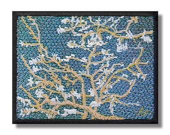 Può includere: Toppa ricamata con una rappresentazione stilizzata di un mandorlo in fiore con fiori bianchi su uno sfondo blu. I rami dell'albero sono di colore marrone chiaro.