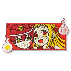 May include: Embroidered patch featuring two anime characters, a boy with red hair and a girl with yellow hair, against a red background. The boy is wearing a red hat and the girl is wearing a yellow dress. The patch has a white border and two white ghost-like figures with yellow eyes.