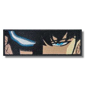 May include: A black and white embroidered patch with a close-up of a blue eye. The eye is looking directly at the viewer.