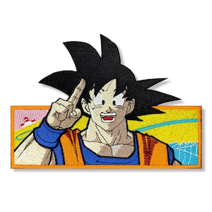 May include: An embroidered patch featuring a cartoon character with spiky black hair, wearing an orange and blue outfit, with a yellow background and a blue sky.