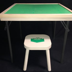 May include: A child's play table with a green building block surface and a matching stool. The table has a light wood frame and dark gray metal legs. The stool is white with a green block design.