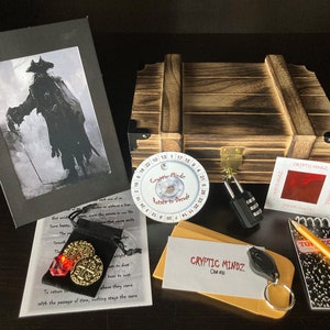 Peut inclure: Un coffre au trésor en bois avec divers objets sur le thème des énigmes. Comprend une impression de pirate en noir et blanc, une roue de code, un cadenas à combinaison, un bloc-notes, un crayon et un petit sac avec des pièces et une gemme rouge. Les objets sont disposés sur une surface sombre.