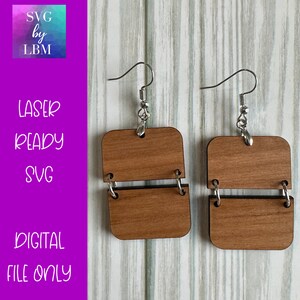 May include: A pair of wooden earrings with a square shape. Each earring is made of two squares that are connected by a metal ring. The earrings are a light brown color and have silver hooks.