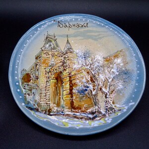 Piatto souvenir in ceramica russa dipinto a mano. Realizzato da artista locale (SP), il piatto in ceramica raffigura un edificio a Bipurina Gora.Ottime condizioni.