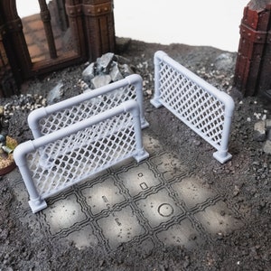 May include: Two white plastic fence sections with a diamond-shaped wire mesh. The fences are on a gray surface with a pattern of squares and circles.