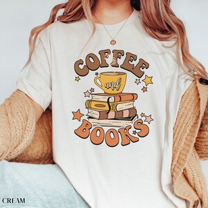 May include: A white t-shirt with the text "Coffee and Books" in brown and orange letters. A cup of coffee and a stack of books are illustrated in the center of the text.