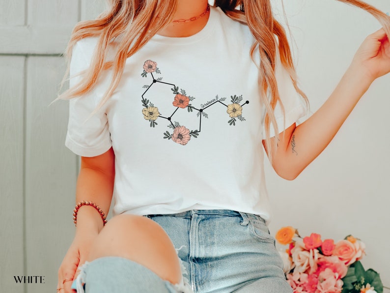May include: White t-shirt with a floral graphic of a chemical structure labeled "serotonin".