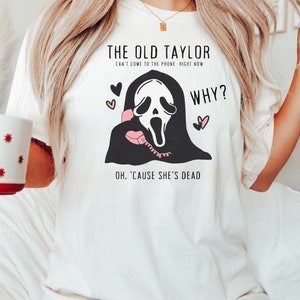 May include: White t-shirt with the text "THE OLD TAYLOR CAN'T COME TO THE PHONE RIGHT NOW WHY? OH, 'CAUSE SHE'S DEAD" and a graphic of a ghost holding a pink telephone. The shirt also features pink hearts.