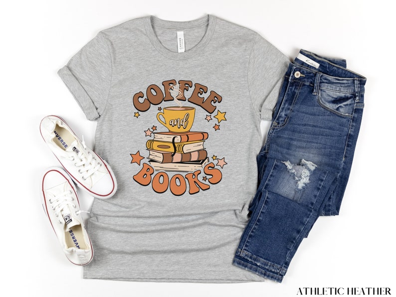 May include: A gray t-shirt with the text "Coffee and Books" in a retro font. The text is surrounded by stars and a cartoon image of a coffee cup on top of a stack of books.