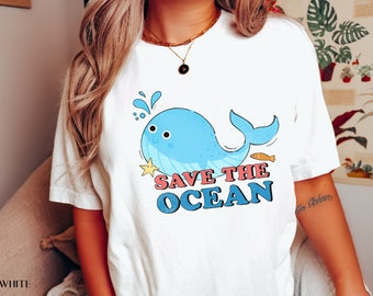 Peut inclure: T-shirt blanc avec un graphique de baleine bleue et le texte "SAVE THE OCEAN" en lettres colorées.