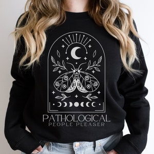 May include: Black sweatshirt with a white graphic design featuring a moth, crescent moon, stars, and the text "Pathological People Pleaser".