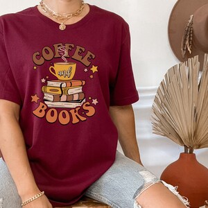 May include: A maroon t-shirt with a graphic design of a coffee cup and books with the text "Coffee and Books" in a retro style.