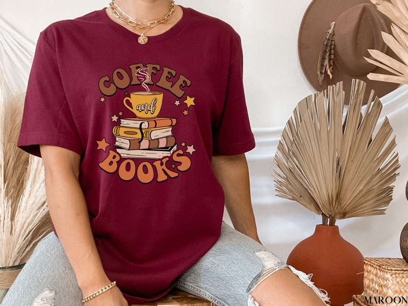 May include: A maroon t-shirt with a graphic design of a coffee cup and books with the text "Coffee and Books" in a retro style.