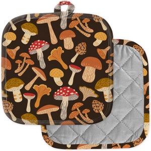 Può includere: Un paio di presine quadrate con sfondo marrone scuro e un motivo ripetuto di vari funghi colorati. I funghi sono in tonalità di rosso, arancione, beige e bianco. Le presine hanno una fodera trapuntata grigia e un piccolo anello per appenderle.