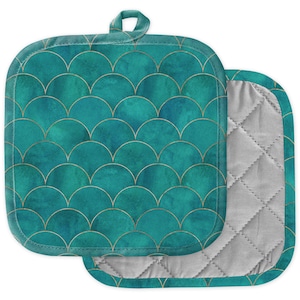 Könnte beinhalten: Zwei quadratische Topflappen in Teal mit einem goldenen Schuppenmuster. Die Topflappen haben eine Schlaufe zum Aufhängen und eine gesteppte graue Innenseite. Die Farbe Teal hat einen Aquarelleffekt.