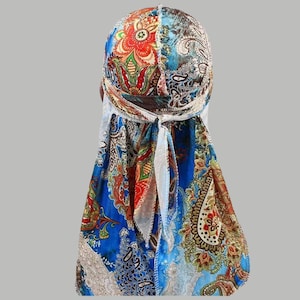 May include: A colorful durag with a paisley and floral pattern in shades of blue, red, and brown. The head covering has a tie closure at the back and is made of a silky material.