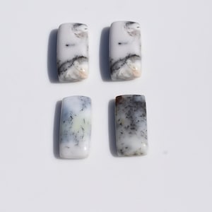 May include: Four rectangular gemstones with a white base and intricate patterns of black and grey. The stones have a polished, smooth surface, and are arranged against a plain white background.