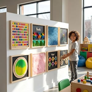 May include: A wall-mounted sensory activity center featuring eight square wooden frames. The panels include a colorful block grid, pinwheels labeled 'Breathe', a blue textured surface, a chalkboard with a flower, a green liquid disc, pink fur, a 'Fidget' gear board, and a 'Turn' gear board.