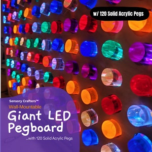 Puede incluir: Un gran tablero de clavijas colorido con 120 clavijas de acrílico sólido. El tablero de clavijas es de montaje en pared y presenta una variedad de colores, incluidos rojo, naranja, amarillo, verde, azul, morado y transparente. El tablero de clavijas está etiquetado como "Giant LED Pegboard" y "Sensory Crafters™".