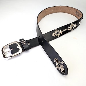 May include: Black leather belt with silver and black studded embellishments. The belt has a silver buckle and is made of genuine leather.