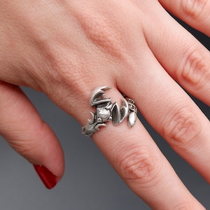 May include: A silver scorpion ring with a detailed design. The ring is worn on a finger.