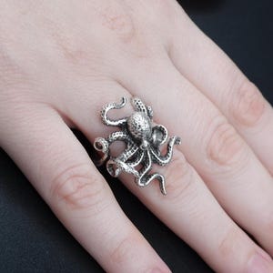 Peut inclure: Bague en argent en forme de pieuvre avec des tentacules détaillés. La bague est portée à un doigt.