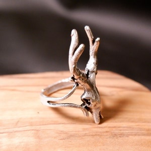 May include: A silver ring with a deer antler design. The ring is made of metal and has a detailed antler design.
