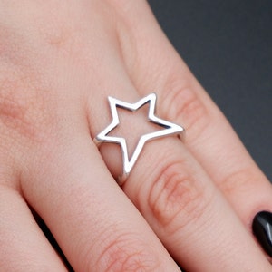May include: A silver ring with a star-shaped design. The star is hollow and has a smooth, polished finish.