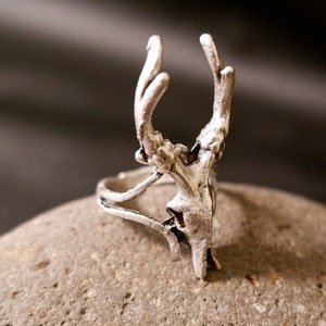 May include: A silver ring with a detailed deer head design. The ring is made of metal and has a delicate, intricate design.