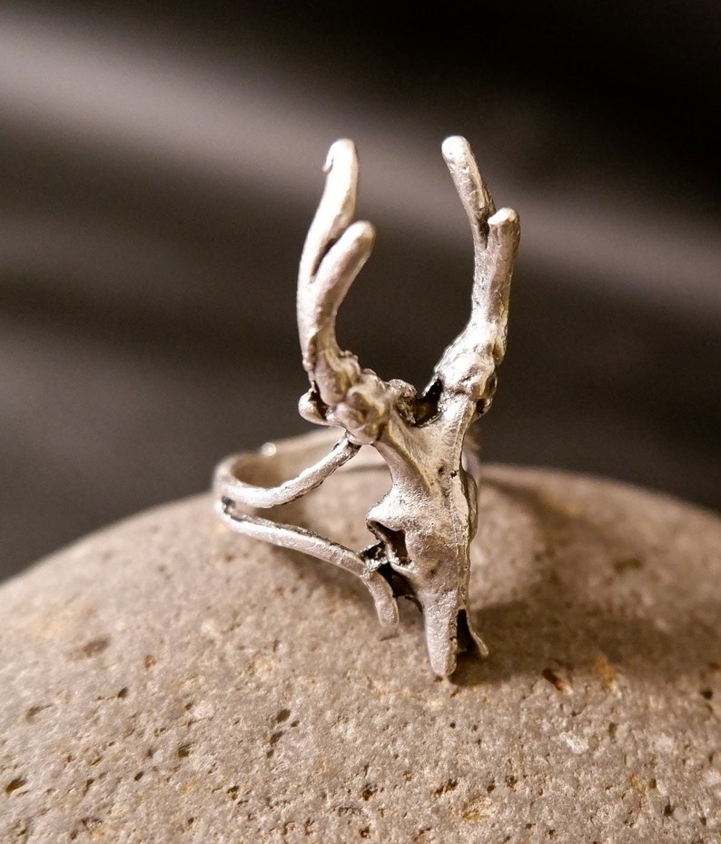 May include: A silver ring with a detailed deer head design. The ring is made of metal and has a delicate, intricate design.