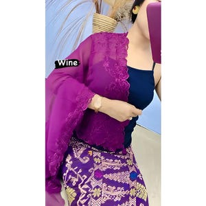 Könnte beinhalten: Outfit einer Frau mit einem dunkelblauen Oberteil, einem lila Schal mit Spitzenbesatz und einem gemusterten Rock. Das Wort "Wine" ist auf dem Bild zu sehen. Der Rock hat goldene und lila Blumenmuster.
