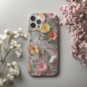 Op de afbeelding: Een telefoonhoesje met een bloemen- en vlinderpatroon. De hoes heeft een lichtgrijze achtergrond met roze, gele en oranje bloemen en vlinders in roze en witte tinten. Het ontwerp bevat goudkleurige wijnranken.