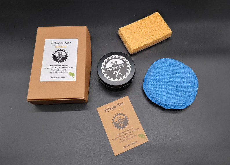 May include: A wood care set with a black tin of wood polish, a blue polishing pad, a yellow sponge, and two brown cardboard boxes with the text "Pflege-Set f&uuml;r Holzpflege" and "100%  lebensmittelechter  langanhaltender  &Ouml;l-Finish  f&uuml;r  wasserabweisend  und  nat&uuml;rlichen  Schutz  Made in Germany".