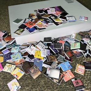Puede incluir: Una gran colecci&oacute;n de libros en miniatura de varios colores y dise&ntilde;os, incluyendo t&iacute;tulos como "Los juegos del hambre", "Bajo la misma estrella" y "El ladr&oacute;n de libros".