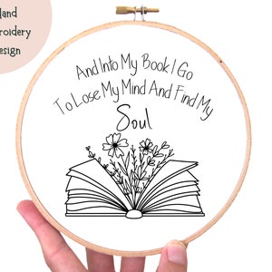 May include: Black and white embroidery design of an open book with flowers growing from it. The text reads "And into my book I go to lose my mind and find my soul."