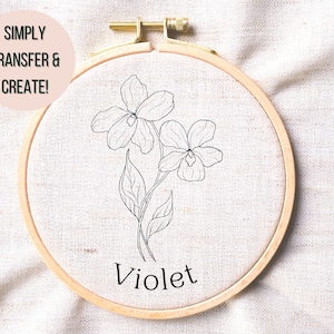 May include: A simple line drawing of a violet flower in a wooden embroidery hoop. The text "Violet" is written below the flower. The text "Simply Transfer & Create!" is written in a pink circle in the top left corner of the image.
