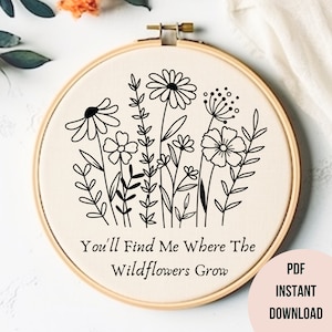 Op de afbeelding: Zwarte en witte borduurring met een ontwerp van wilde bloemen en de tekst "You'll Find Me Where The Wildflowers Grow".
