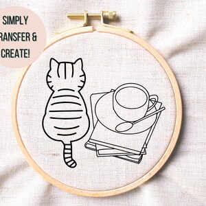May include: A black and white line drawing of a cat sitting next to a stack of books with a cup of coffee on top. The image is on a white fabric background.