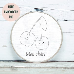 May include: A black and white embroidery pattern of two cherries with faces and the text "Mon chéri" on a white background.