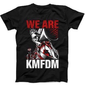 May include: A black short-sleeved t-shirt featuring a graphic print of a person with a mohawk hairstyle wearing sunglasses and holding a megaphone. The text WE ARE appears in red above the figure, and the text KMFDM appears in white below.