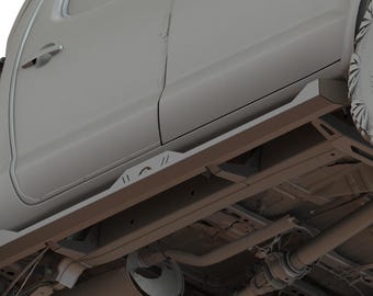 Op de afbeelding: Onderzijde van een grijze pick-up truck met zwarte banden en een zwarte treeplank. De truck is opgehoogd en heeft een grote band aan de rechterkant.