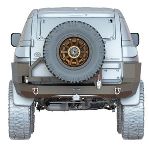 May include: Rear view of a silver SUV with a black spare tyre mounted on the back. The vehicle has a custom rear bumper with a tow hitch and two D-rings.