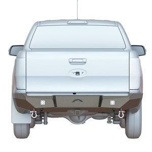 Puede incluir: Vista trasera de una camioneta plateada con un parachoques trasero personalizado. El parachoques tiene dos anillos en D y un enganche de remolque. La camioneta está sobre un fondo blanco.