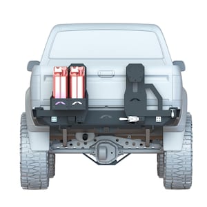 Può includere: Un pick-up bianco con un paraurti posteriore nero e un portapacchi per pneumatici di scorta. Il pick-up ha due taniche di benzina rosse in un rack di stoccaggio sul portellone.