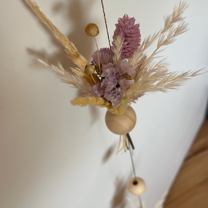 Suspension murale décorative. Une guirlande avec des perles en bois et des bouquets de fleurs séchées. Fleurs et couleurs au choix