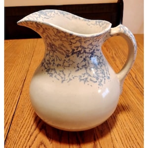 May include: A set of three ceramic mugs with a speckled, matte finish. The mugs are in shades of cream, light gray, and dark gray. Each mug has a simple, minimalist design and a rounded handle.